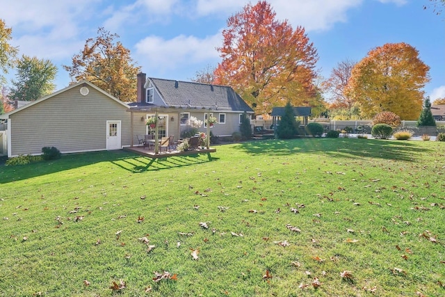 rear view of property featuring a chimney and a lawn