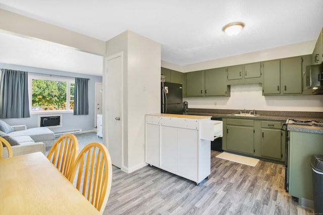 kitchen with light hardwood / wood-style floors, green cabinets, black refrigerator, and sink