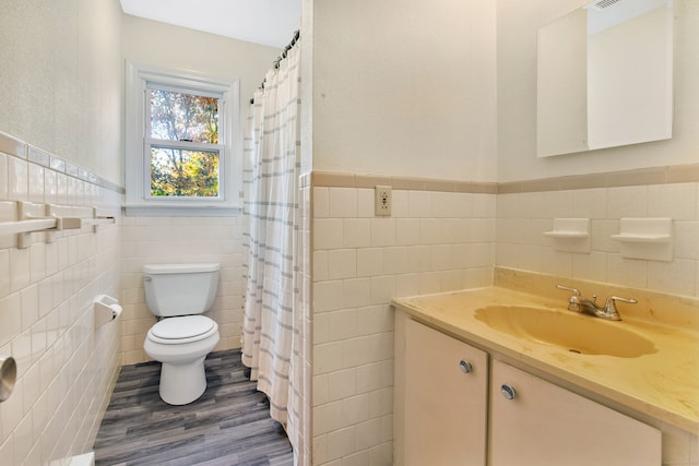 bathroom with walk in shower, hardwood / wood-style flooring, tile walls, toilet, and vanity