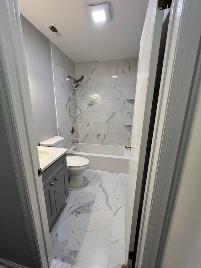 full bathroom featuring vanity, tiled shower / bath, and toilet