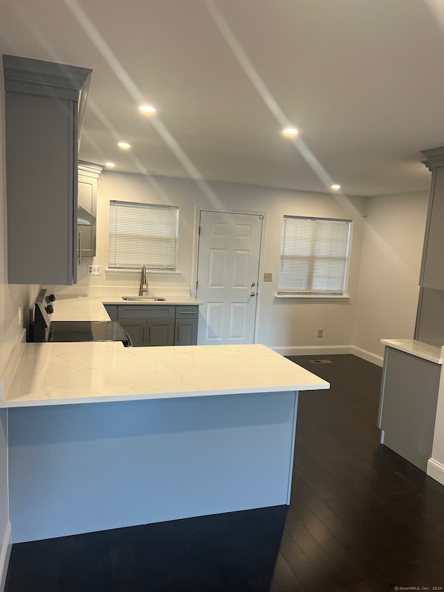 kitchen with gray cabinets, kitchen peninsula, stove, and sink