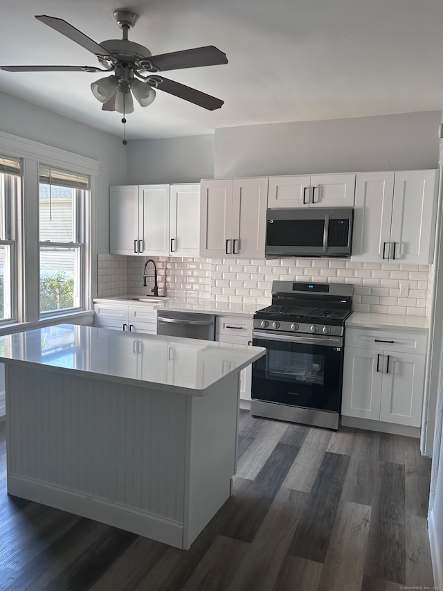 kitchen featuring ceiling fan, appliances with stainless steel finishes, backsplash, white cabinetry, and dark hardwood / wood-style floors