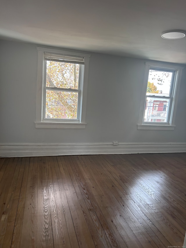 empty room featuring dark wood-type flooring and plenty of natural light