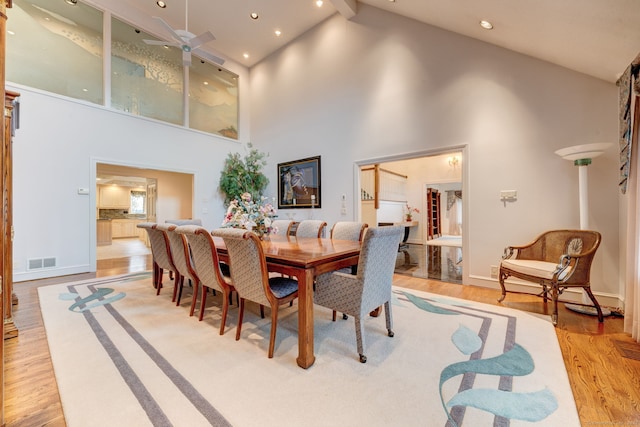 dining space with high vaulted ceiling, light hardwood / wood-style floors, beamed ceiling, and ceiling fan