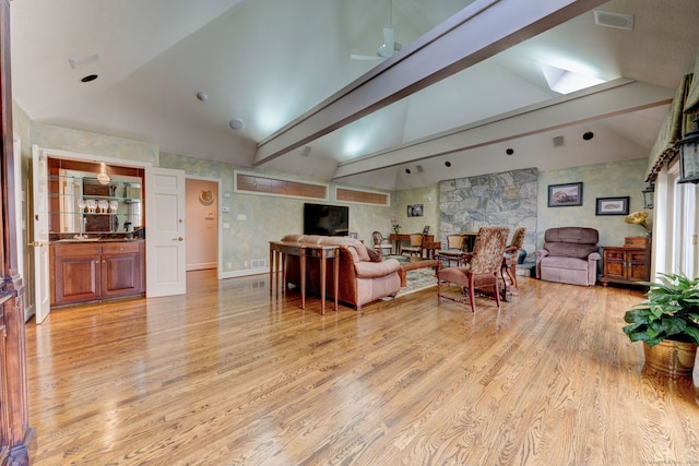 living room with lofted ceiling with beams, ceiling fan, and light wood-type flooring