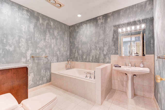 bathroom with a relaxing tiled tub, tile patterned flooring, toilet, and tile walls