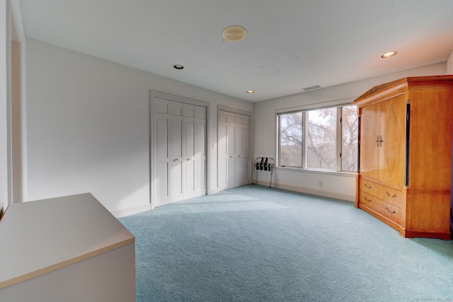 unfurnished bedroom with multiple closets and light colored carpet