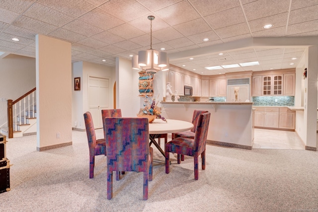 dining space with light colored carpet and a paneled ceiling