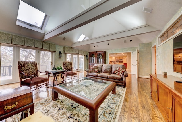 living room with lofted ceiling with skylight, french doors, and light hardwood / wood-style floors