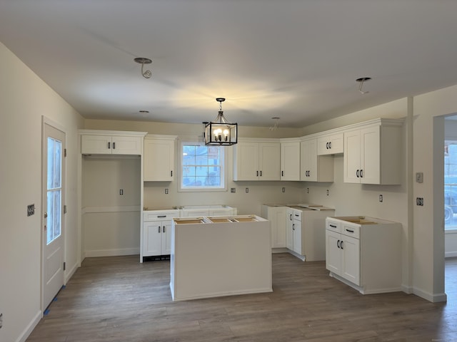 kitchen with a center island, decorative light fixtures, light hardwood / wood-style flooring, a notable chandelier, and white cabinetry