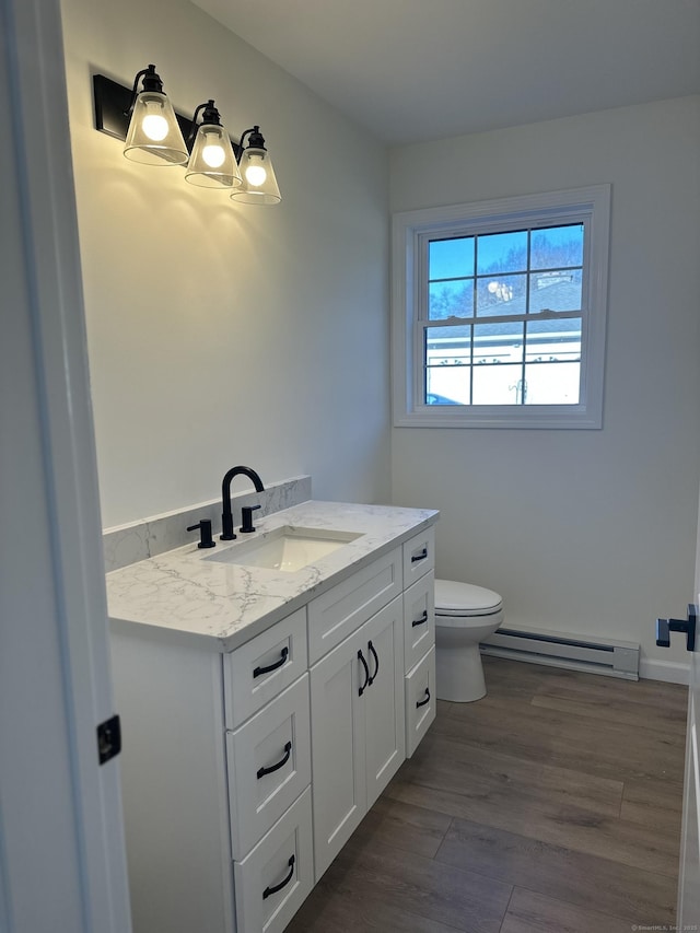 bathroom with vanity, wood-type flooring, toilet, and baseboard heating