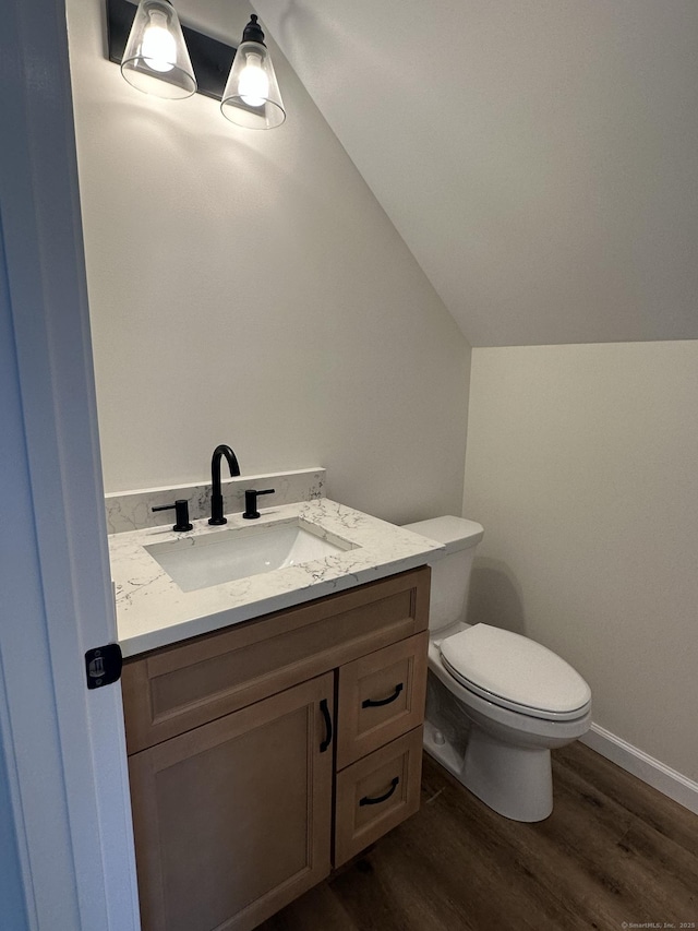 bathroom with hardwood / wood-style flooring, vanity, toilet, and vaulted ceiling