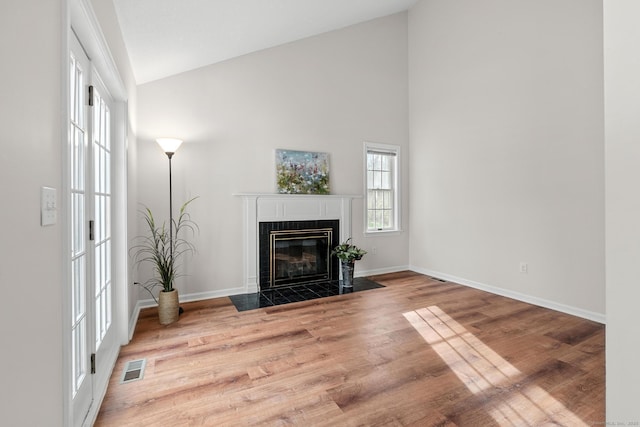 living room with light wood-type flooring, a fireplace, and high vaulted ceiling