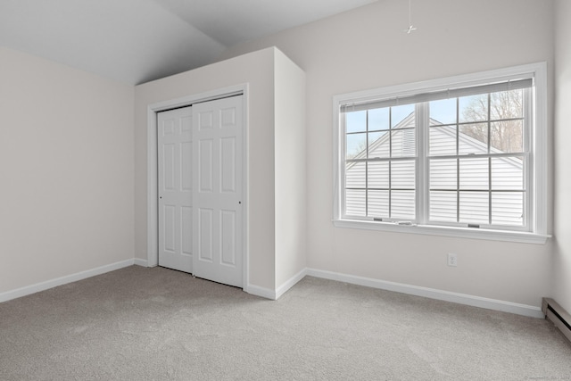 unfurnished bedroom featuring a baseboard radiator, a closet, light carpet, and vaulted ceiling