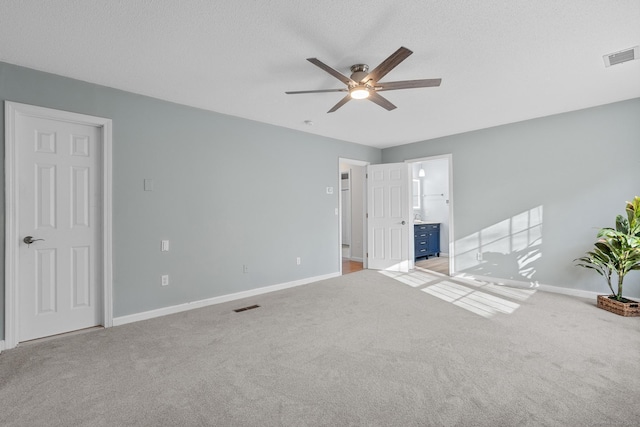 interior space featuring a textured ceiling, ceiling fan, connected bathroom, and carpet floors