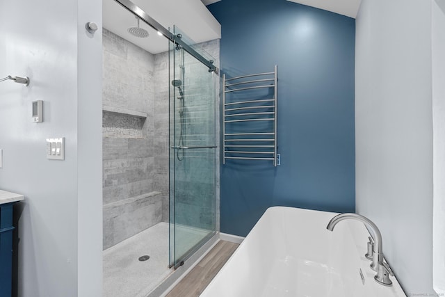 bathroom featuring wood-type flooring, radiator, vanity, and plus walk in shower