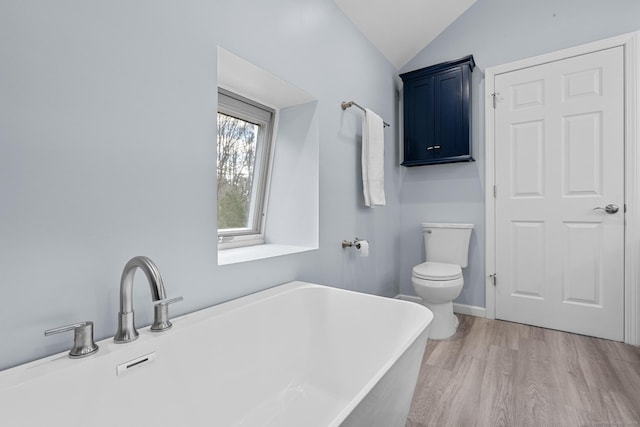 bathroom featuring vaulted ceiling, toilet, wood-type flooring, and a tub