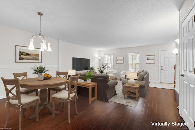 living room with dark wood-type flooring, an inviting chandelier, and a textured ceiling