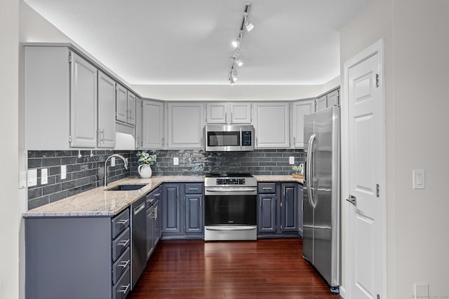 kitchen featuring gray cabinets, stainless steel appliances, dark hardwood / wood-style floors, light stone countertops, and sink