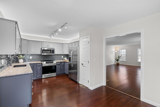 kitchen with light stone countertops, stainless steel appliances, sink, dark hardwood / wood-style floors, and gray cabinets