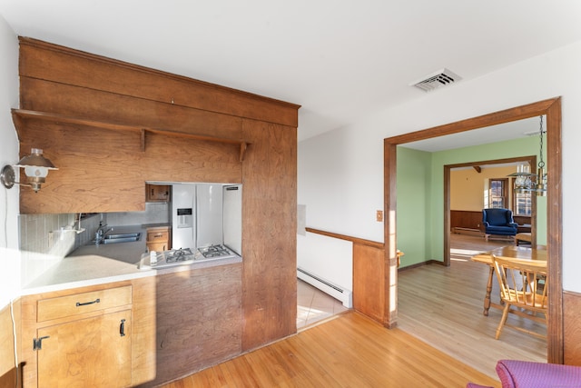 kitchen featuring white appliances, sink, baseboard heating, tasteful backsplash, and light hardwood / wood-style floors