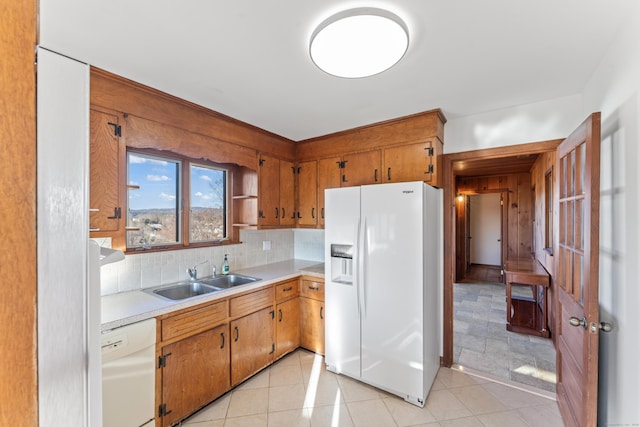 kitchen featuring decorative backsplash, light tile patterned floors, white appliances, and sink