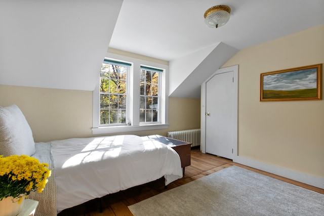 bedroom featuring vaulted ceiling, light hardwood / wood-style floors, and radiator