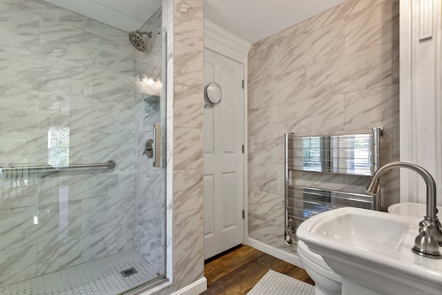 bathroom with a shower with door, wood-type flooring, sink, toilet, and tile walls