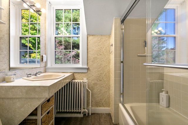 bathroom with tiled shower / bath, sink, hardwood / wood-style floors, and radiator