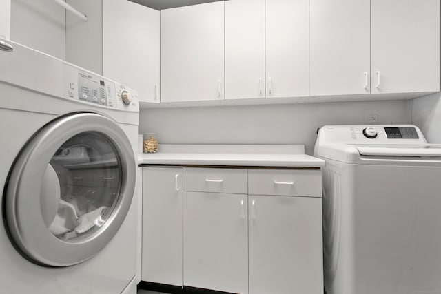 clothes washing area with independent washer and dryer and cabinets