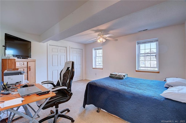 bedroom featuring ceiling fan, multiple windows, and light colored carpet