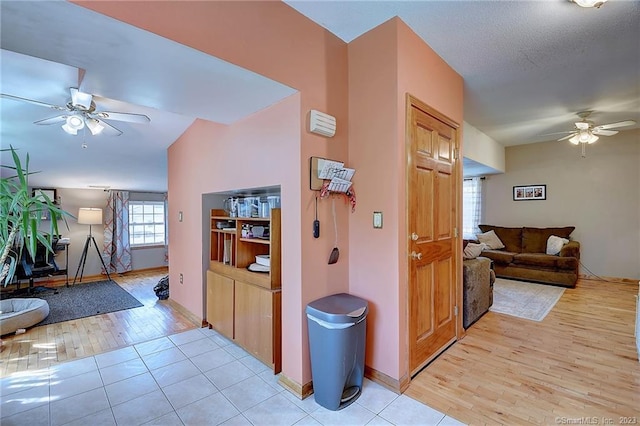 hall featuring vaulted ceiling, a textured ceiling, and light hardwood / wood-style floors