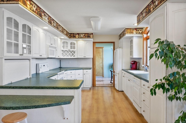 kitchen featuring sink, kitchen peninsula, light hardwood / wood-style floors, white appliances, and white cabinets