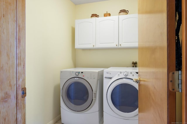 clothes washing area featuring cabinets and separate washer and dryer