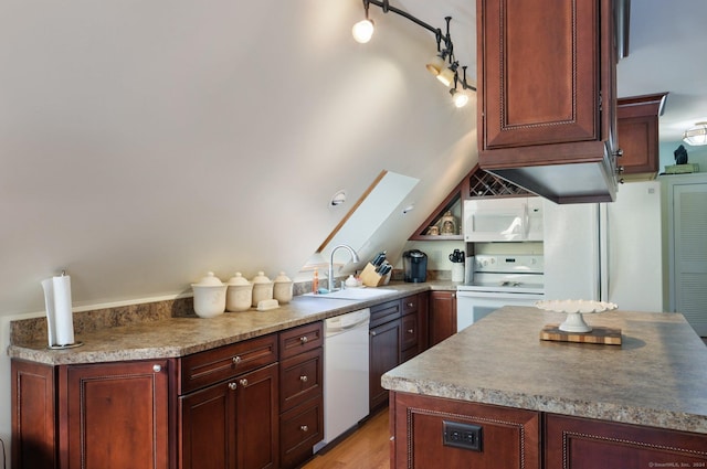 kitchen with a skylight, white appliances, sink, and light hardwood / wood-style flooring