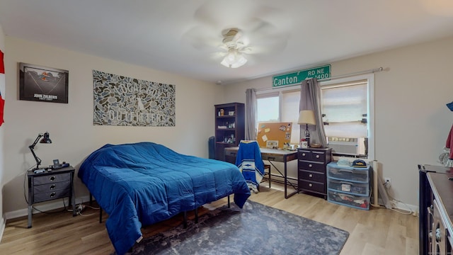 bedroom with baseboards, ceiling fan, a baseboard heating unit, and wood finished floors