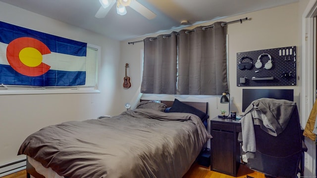 bedroom with a baseboard heating unit, a ceiling fan, and wood finished floors