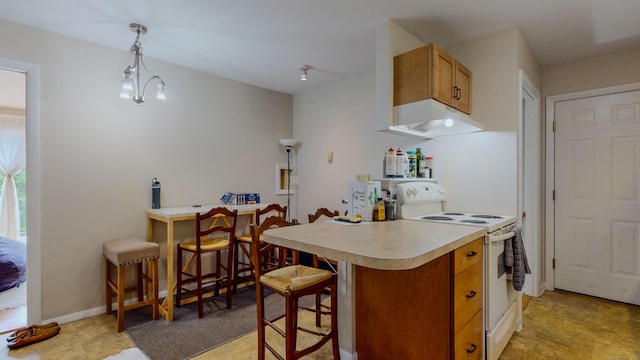 kitchen featuring light countertops, electric range, brown cabinetry, a peninsula, and a kitchen bar