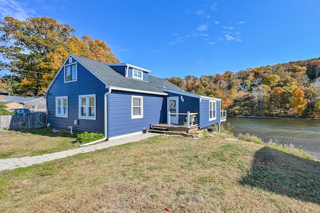 rear view of property featuring a deck with water view and a yard