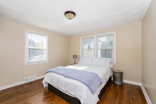 bedroom featuring multiple windows and dark hardwood / wood-style floors