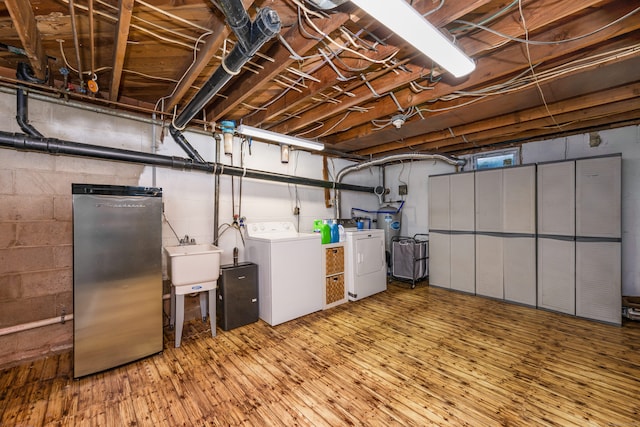 basement featuring independent washer and dryer, sink, hardwood / wood-style floors, and stainless steel refrigerator