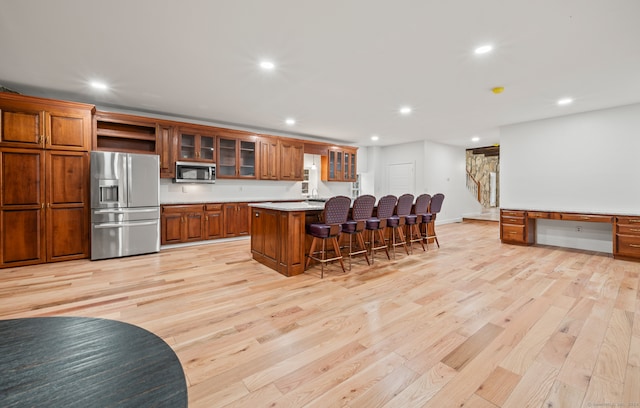 kitchen featuring a kitchen island, light hardwood / wood-style flooring, appliances with stainless steel finishes, and a breakfast bar area