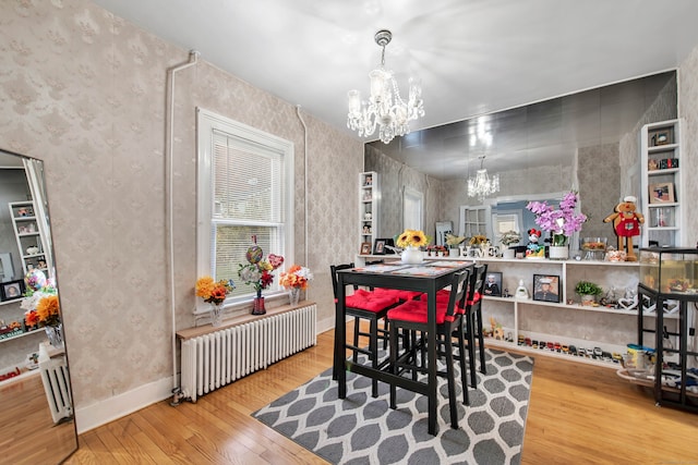 dining room with light hardwood / wood-style flooring, a notable chandelier, and radiator