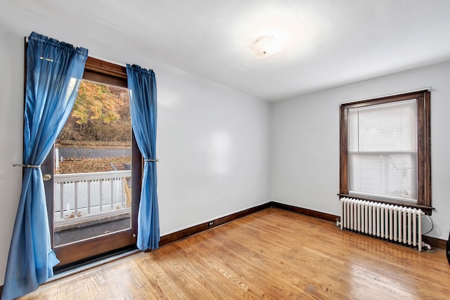 empty room featuring radiator heating unit and hardwood / wood-style flooring