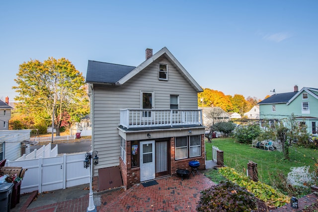 back of property with a yard and a balcony