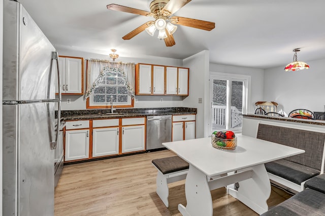 kitchen featuring white cabinets, light wood-type flooring, sink, decorative light fixtures, and stainless steel appliances