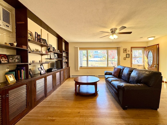 living room with a textured ceiling, light wood-type flooring, and a healthy amount of sunlight