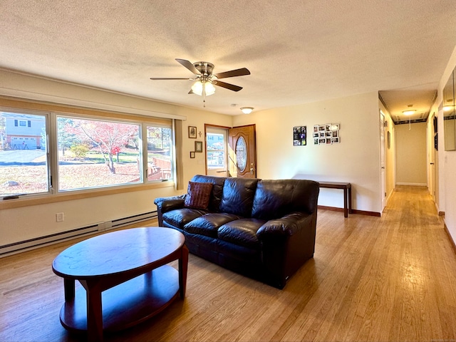 living room featuring ceiling fan, a baseboard radiator, light hardwood / wood-style floors, and a textured ceiling