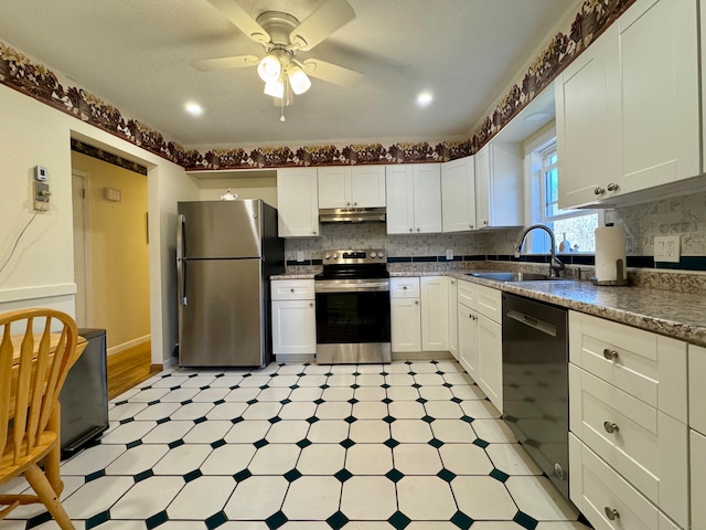 kitchen with decorative backsplash, stainless steel appliances, ceiling fan, sink, and white cabinetry