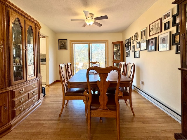 dining area featuring a baseboard radiator, ceiling fan, light wood-type flooring, and a textured ceiling